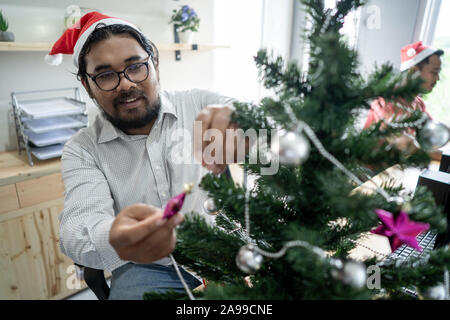 Glückliche Arbeiter schmücken Weihnachtsbaum Stockfoto