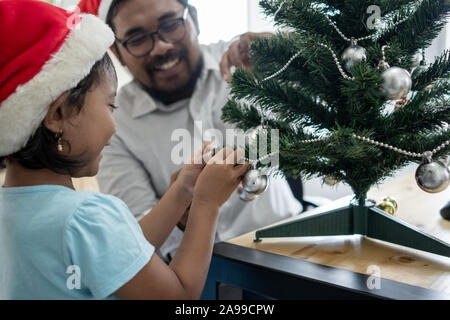 Gerne Vater Arbeiter schmücken Weihnachtsbaum mit seiner Tochter Stockfoto