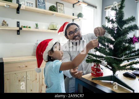 Gerne Vater Arbeiter schmücken Weihnachtsbaum mit seiner Tochter Stockfoto