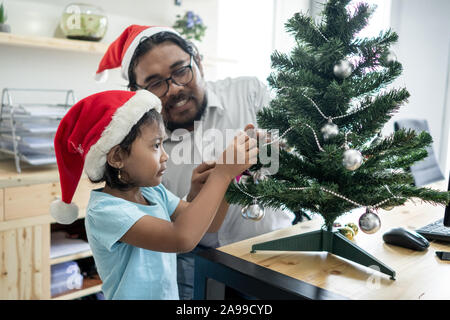 Gerne Vater Arbeiter schmücken Weihnachtsbaum mit seiner Tochter Stockfoto