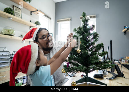 Gerne Vater Arbeiter schmücken Weihnachtsbaum mit seiner Tochter Stockfoto