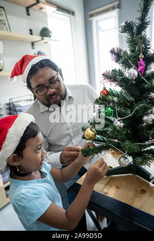 Gerne Vater Arbeiter schmücken Weihnachtsbaum mit seiner Tochter Stockfoto