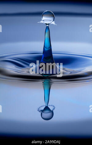Ein wassertropfen Form erstellt, wenn zwei Tropfen kollidieren auf der Oberfläche des blauen Wasser, die eine schöne Reflexion. Tropfen Kunst, Wasser tropfen Fotografie Stockfoto