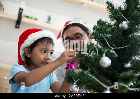 Gerne Vater Arbeiter schmücken Weihnachtsbaum mit seiner Tochter Stockfoto