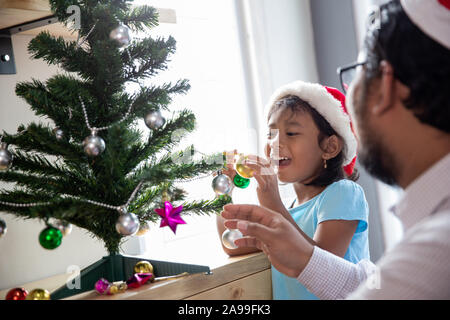 Gerne Vater Arbeiter schmücken Weihnachtsbaum mit seiner Tochter Stockfoto
