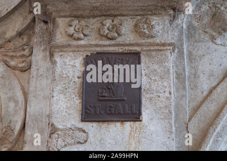 Bild von einem Bügeleisen Plakette, die Swiss Helvetia Emblem und das Skript St. Gallen auf eine schöne verzierte Steinmauer im Dorf Casl entfernt Stockfoto