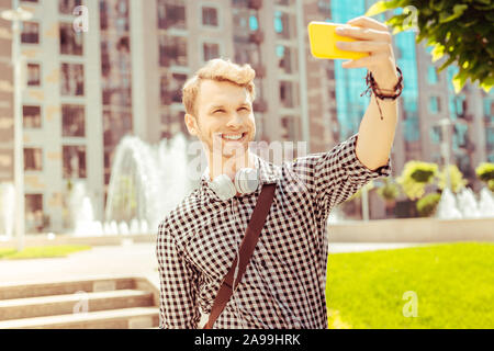 Fröhliche blonde Mann unter selfie Foto im Park Stockfoto