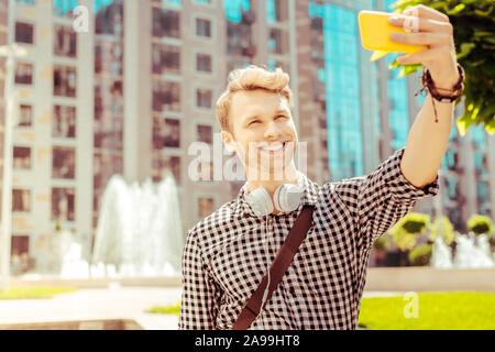 Positiv erfreut, blonder Mann tun selfie Foto Stockfoto