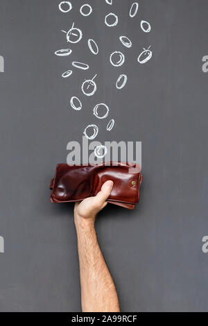 Verdienen Sie Geld mit einem braunen Lederetui in einer Hand vor einer Tafel mit Hand gezeichnet Münzen statt Stockfoto