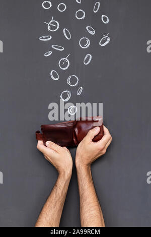 Verdienen Sie Geld mit einem braunen Lederetui in zwei Händen vor einer Tafel mit Hand gezeichnet Münzen statt Stockfoto