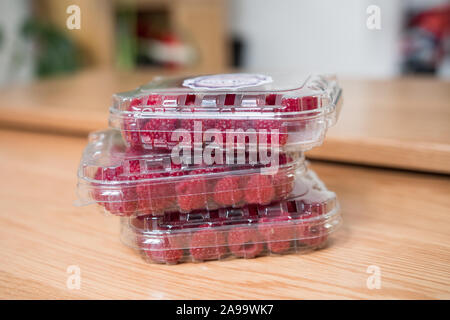 Lecker und sehr bunte Himbeeren in nicht umweltfreundliche Kunststoffbehälter (Recycling ist ursprüngliches). 3 Boxen liegen auf einem Holztisch. Markt Früchte. Stockfoto