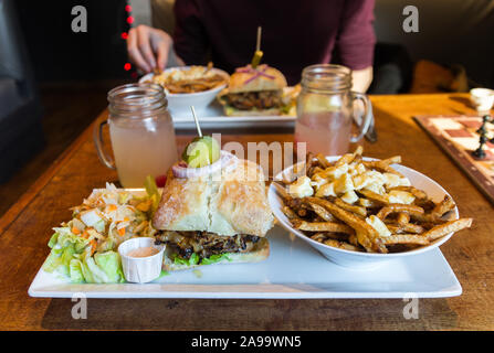 Köstliche Poutine, Burger, Pommes und frischen Salat an Hippi Poutine in Montreal (Quebec, Kanada). Schöne Nahaufnahme dieser leckeren kanadischen Mahlzeit. Lecker Stockfoto