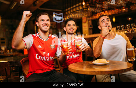 Party aufgeregt Arsenal Fans beobachten Fußball mit Ganzberg Bier in Das Pub Stockfoto