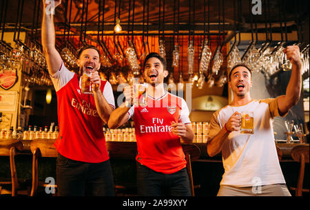 Party aufgeregt Arsenal Fans beobachten Fußball mit Ganzberg Bier in Das Pub Stockfoto