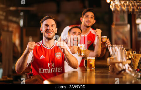 Party aufgeregt Arsenal Fans beobachten Fußball mit Ganzberg Bier in Das Pub Stockfoto