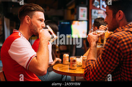 Party aufgeregt Arsenal Fans beobachten Fußball mit Ganzberg Bier in Das Pub Stockfoto