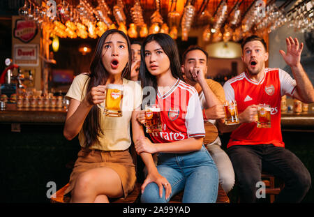 Party aufgeregt Arsenal Fans beobachten Fußball mit Ganzberg Bier in Das Pub Stockfoto