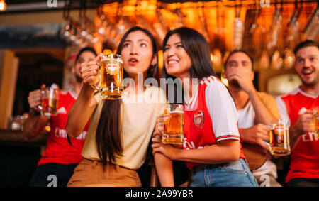 Party aufgeregt Arsenal Fans beobachten Fußball mit Ganzberg Bier in Das Pub Stockfoto