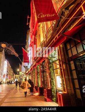 Weihnachtsdekorationen an der New Bond Street in London mit der roten Fassade von Cartier. Stockfoto