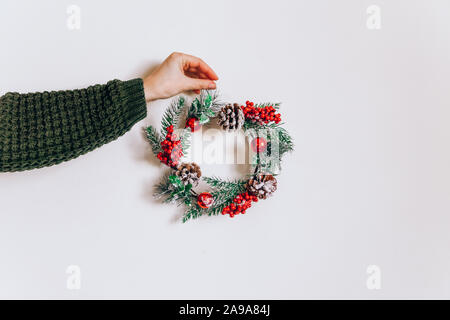 Kranz Rahmen aus Kiefer und Weihnachten Einrichtung in weibliche Hände auf einem hellen Hintergrund. Flach, eleganten Stil. Weihnachten, Silvester, Vorbereitung für die Ho Stockfoto