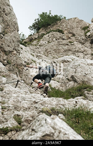 Männliche Bergsteiger in steilen senkrechte Wand klettern die Klettersteige in den Julischen Alpen. Alpinismus, Bergsteigen und Schutzausrüstung Konzepte Stockfoto