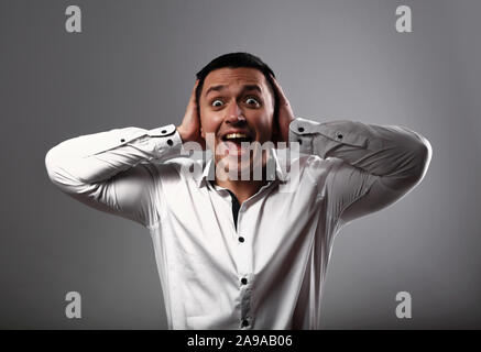 Schreien entsetzt Young Business Mann, mit weit geöffnetem Mund und an der Hand der Kopf auf grauen Hintergrund. Closeup emotion Portrait Stockfoto