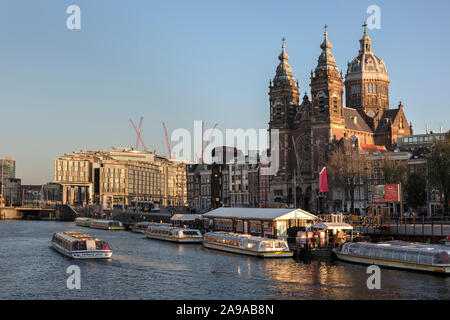 Amsterdam, Holland - Oktober 10, 2019: St. Nikolaus Basilika an der Prins Hendrikkade nahe dem Oudezijds Kolk Wasser bei Sonnenuntergang Stockfoto