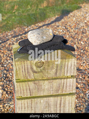 Ein paar der verlorenen Handschuhe auf einem hölzernen Pfosten am Strand in North Norfolk an Salthouse, Norfolk, England, Vereinigtes Königreich, Europa. Stockfoto