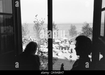 Zwei junge Frauen, die an einem Fenster nach unten schaut in einem Café Terrasse am Chiemsee, Deutschland 1930. Stockfoto