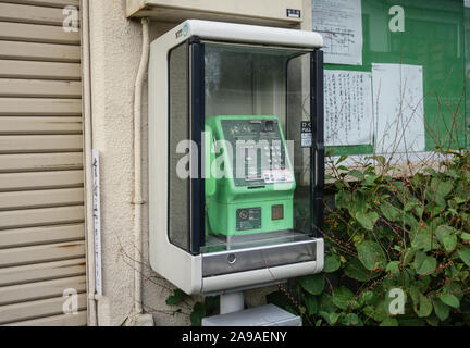 Altes grünes japanisches öffentliches Telefon in einem Schrank an der Seite der Straße Stockfoto