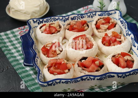 Gebackene Champignons gefüllt mit Tomaten unter suluguni Käse, eine festliche warme Snacks der georgischen Küche, Prozess der Vorbereitung Stockfoto