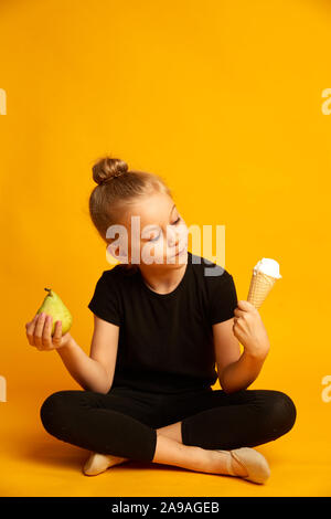 Kleine Tänzerin die Wahl zwischen Birnen und Eis verwirrt Stockfoto