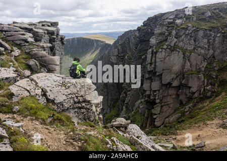 Eine Frau, die die Aussicht in der Nähe des Gipfels von Lochnagar, einem Munro in Aberdeenshire, Schottland, betrachtet. Stockfoto