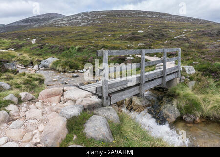 Blick auf eine Holzbrücke auf dem Weg zum Gipfel von Lochnagar, einem Munro in Aberdeenshire, Schottland. Stockfoto