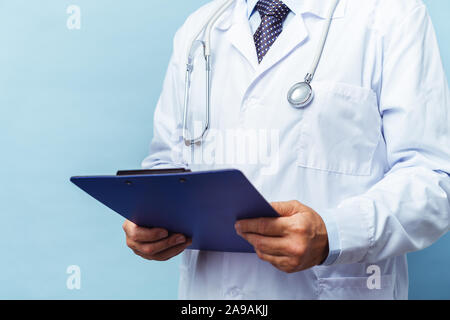 Medizinische leitender Arzt mit einem Stethoskop. Auf einem blauen Hintergrund. Der Arzt hält die Ordner in der Hand und macht einen Termin in der Klinik Stockfoto