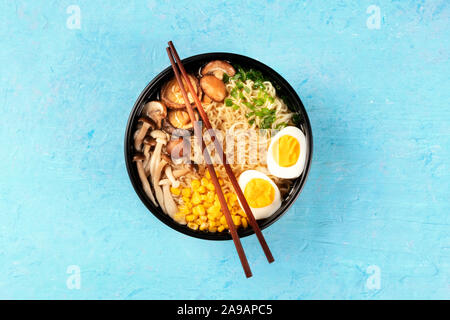 Ramen. Soba Nudeln mit gekochten Eiern, Shiitake-pilze, und Gemüse, schossen ausdem oben auf blauem Hintergrund mit Stäbchen Stockfoto