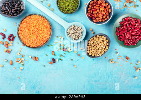 Hülsenfrüchte, Schuß von der Oberseite auf blauem Hintergrund mit einem Platz für Text. Lebendige Impulse einschließlich bunte Bohnen, Linsen, Kichererbsen, eine flache Komposition legen Stockfoto