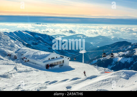 Winter Berge. Schneebedeckten Gipfeln und Nebel in den Tälern. Blau und rosa Himmel über die Skipiste. Skilift und Bar Stockfoto