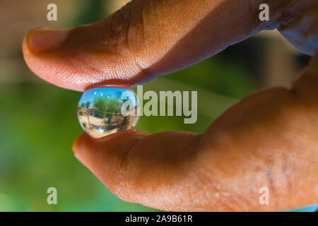 Reflexion in einem Haus in einer Hydro gel Ball. Ein Haus in ein Hydro Ball mit grünem Hintergrund verschwommen. Stockfoto