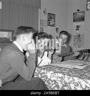 Drei Jungen mit Mundharmonika und gutar Ihre Lieblingssongs abspielen, Deutschland 1956 Stockfoto