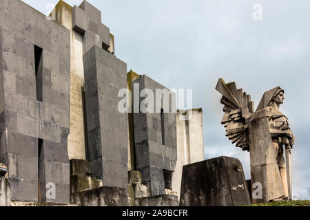 Friedhofseingang, bewacht von Angel of Tod in Azul, Argentinien. Zwei ewige Flammen auf jeder Seite eines gigantischen Rippen, der 50 Fuß groß ist. Stockfoto