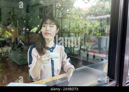 Schöne junge geschäftsfrau glücklich und erfolgreich halten Kaffee Tasse sitzen neben dem Fenster. Stockfoto