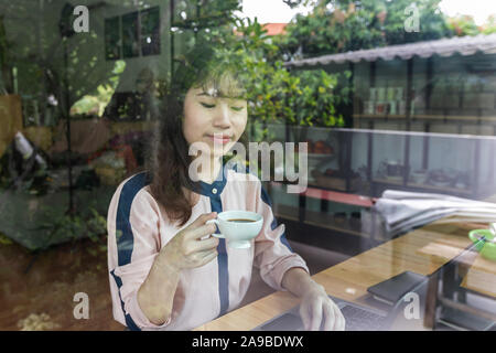 Schöne junge geschäftsfrau glücklich und erfolgreich halten Kaffee Tasse sitzen neben dem Fenster. Stockfoto