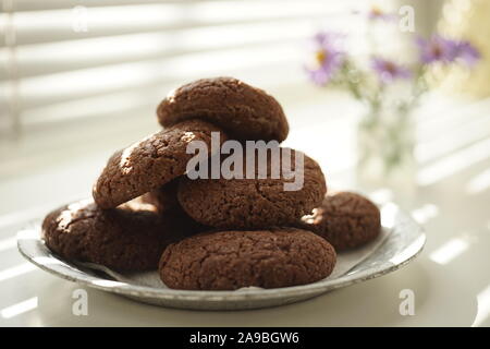 Haferflocken Cookies in einer Platte close-up auf einem Hintergrund von Jalousien und ein Blumenstrauß Stockfoto