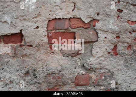 Alte ruiniert Wand mit heraus haften Fragmente aus roten Ziegeln und Zement in der Bohrung Stockfoto