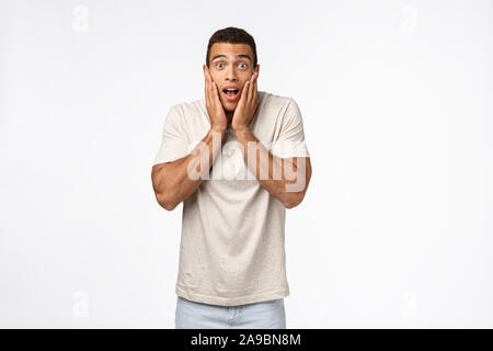 Erschrocken, erstaunt junge muscline Mann sprachlos und fasziniert, schnappen Sie sich Angesicht vor Erstaunen, Kiefer und starren Kamera begeistert, etwas sehen Stockfoto