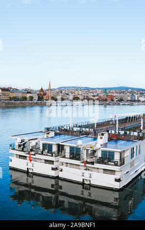 Donau in Budapest, Ungarn mit großen Kreuzfahrtschiff an einem kalten Wintertag. Das historische Zentrum der ungarischen Hauptstadt im Hintergrund. Das umweltfreundliche Verkehrsmittel. Stockfoto