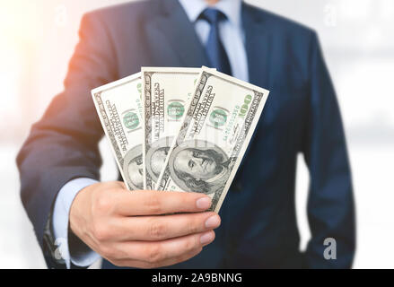 Mann im Anzug hält hundert Dollar Banknoten. Geschäfts-, Finanz- und Gehalt Konzept Stockfoto