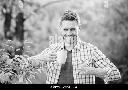 Hervorragender Geschmack. Genießen Sie heiße Getränke. Natürliche trinken. Gesunde Lebensweise. Ich bevorzuge grünen Tee. Erfrischendes Getränk. Man bärtige Kaffee Bauer halten Becher Natur Hintergrund. Grüner Tee Plantage. Vollständige blatt Tee. Stockfoto