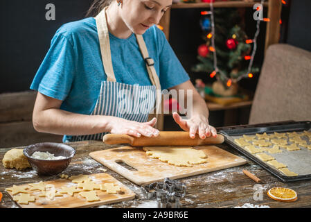 Junge Frau Hausfrau macht Teig für Kochen urlaub Ingwer Cookies auf einen hölzernen Tisch. Gemütliche Atmosphäre am Abend am Heiligabend Stockfoto